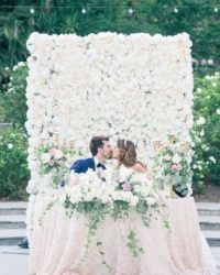 a-white-flower-wall-that-is-used-as-a-backdrop-for-the-ceremony-and-for-the-reception